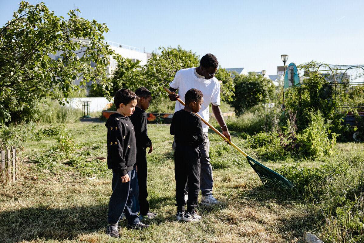 Un volontaire en Service Civique fait du jardinage avec des enfants.